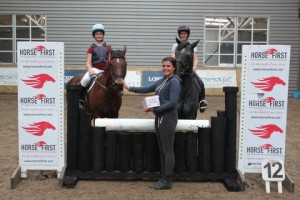 Aoife Hughes of sponsors Horse First presents Tess Meade and Chester with their class prize watched by Victoria Craig and Rocky who were also clear in the 85cm class at Ravensdale Lodge's indoor arena eventing league on Saturday. 