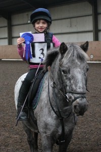 PJ and Emma Bamford hold up their blue rosette. Photo by Equi-Tog