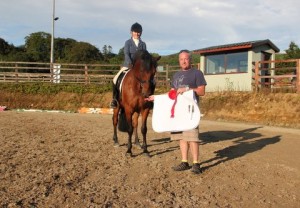 "Wide smiles & long shadows" Eithne O' Hanrahan's smile says it all as she collects her prize from judge David Patterson after winning class 1 with Murray on a hot evening at Ravensdale Lodge's outdoor dressage league final on Tuesday evening. Photo: Niall Connolly.